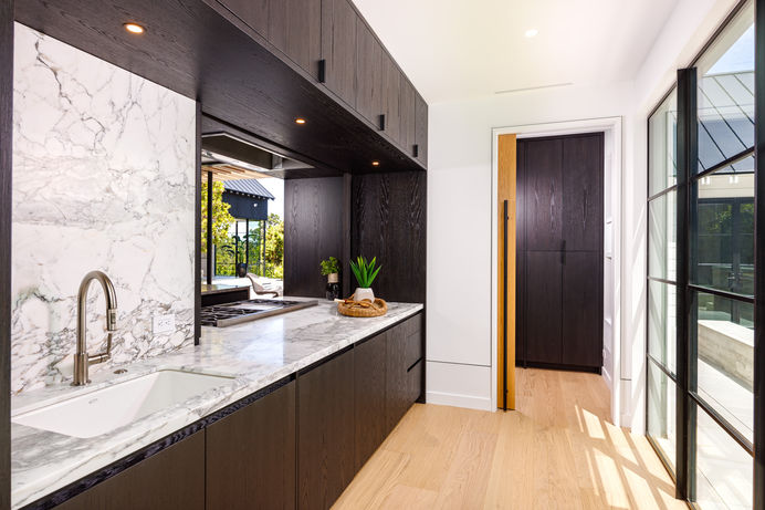 Modern butler's kitchen with granite countertops, sink, and cabinetry.  A walk-in pantry provides additional storage. Real estate photography by Adam Dubich Photography, Orange County, California.