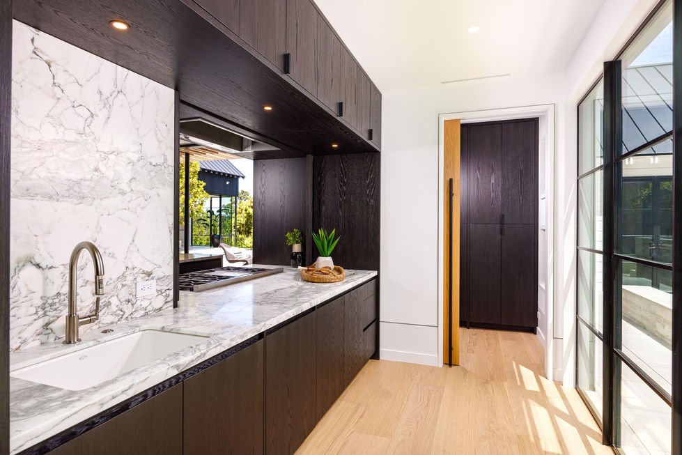 a kitchen with black cabinets and marble counter tops in butlers kitchen