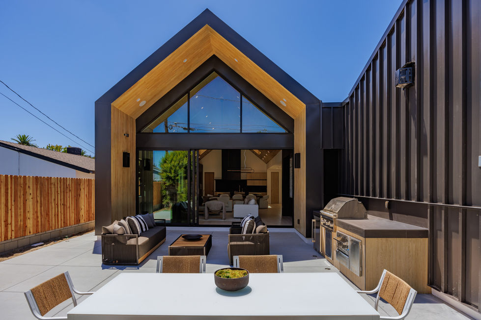 a patio area with a table and chairs in front of a house