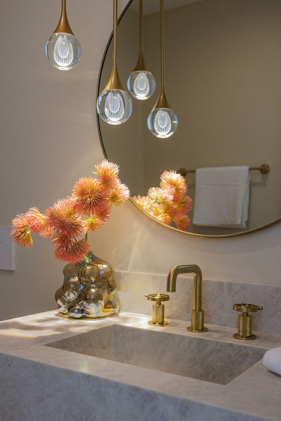 a bathroom sink with a vase of pink flowers on it