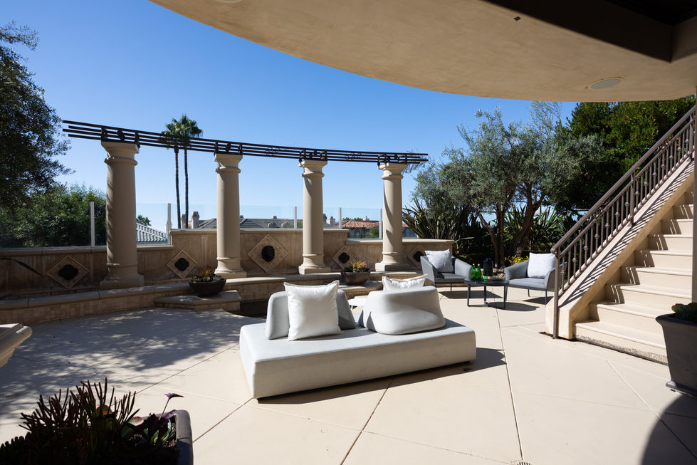 a patio with a couch and chairs and columns