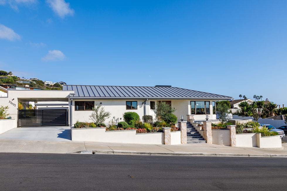 a white house with a metal roof sits on a sunny day