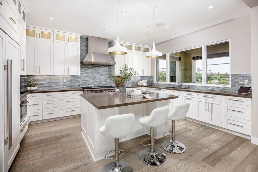 a kitchen with white cabinets and stools and a large island