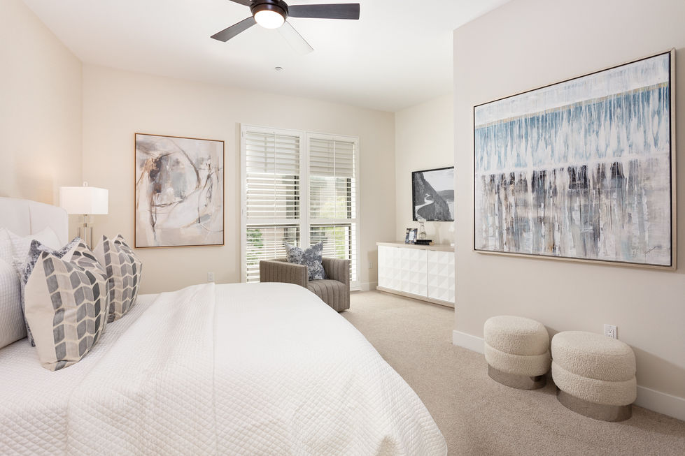 a bedroom with a ceiling fan and two paintings on the wall