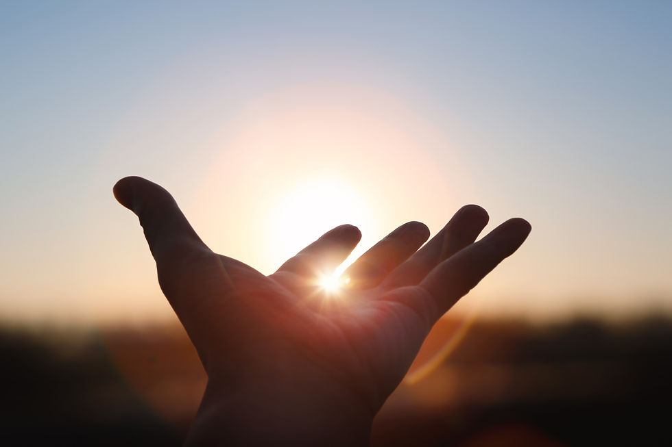 Hands stretched out toward the rising sun at New Year's sunrise, brilliant light shining b