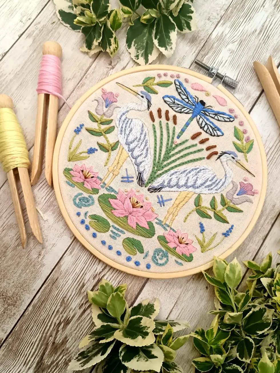 Close up of dragonfly pond embroidery design stitched on natural calico fabric