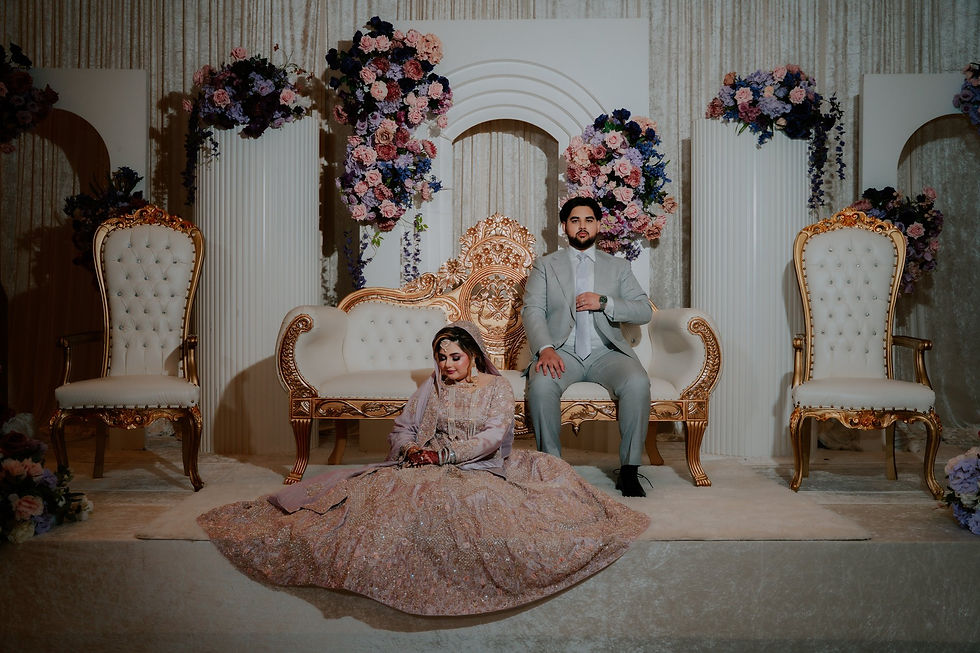 Nooria and Owais on their floral reception stage with white arches and gold seating at The Bellevue, Chantilly VA