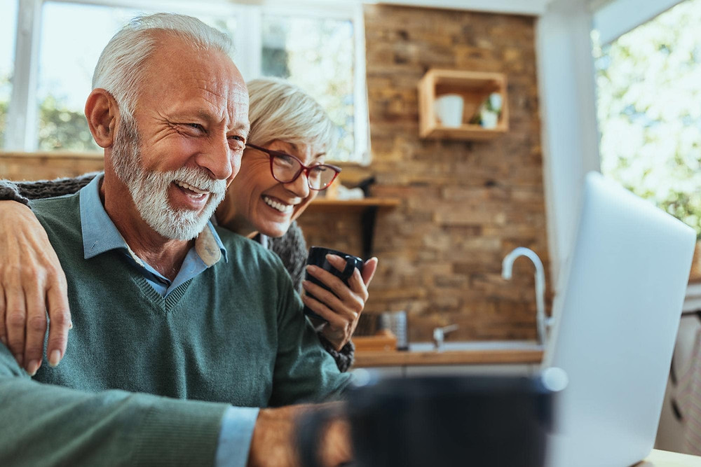 An older couple looking at their laptop and smiling