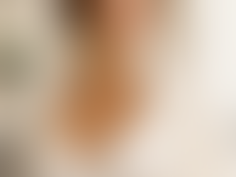 Elegant portrait of a fit woman in a cream silk top and white blazer, standing in a bright luxury interior with soft natural lighting and a refined, natural silhouette.