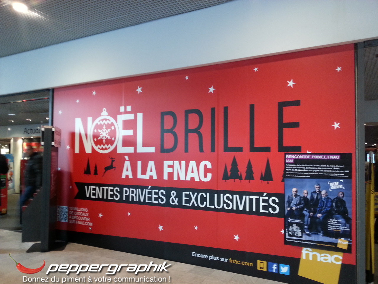 Grande bâche publicitaire rouge Noël brille à la FNAC posée sur la devanture d'un magasin par Peppergraphik au Havre