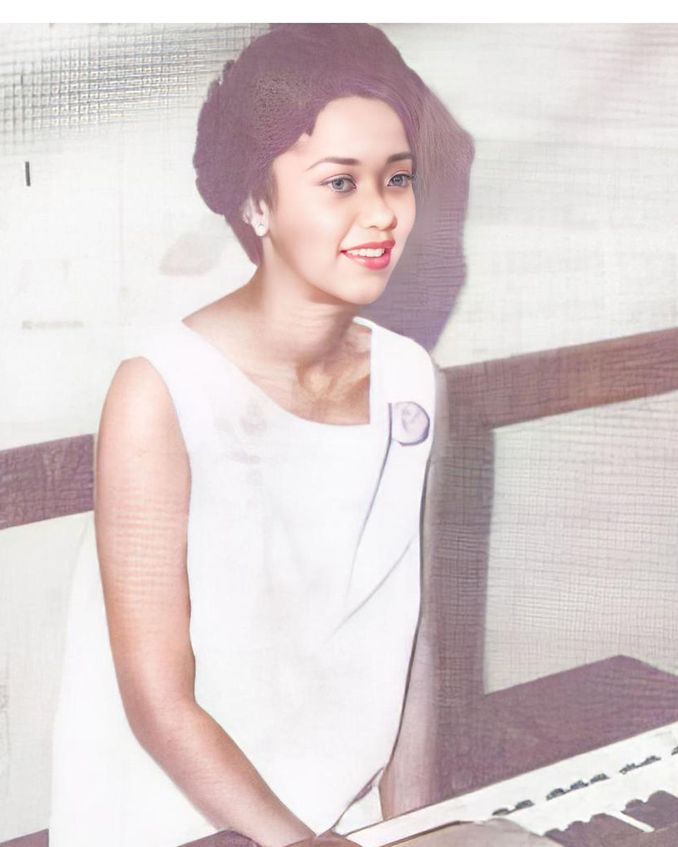 A smiling Erica Allen in a white dress seated at a piano.