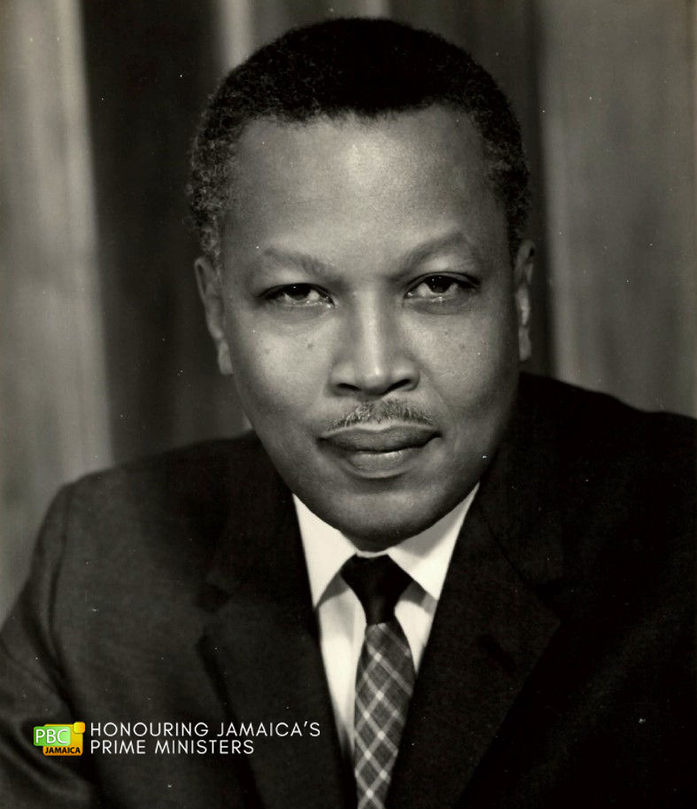 Monochrome portrait of Hugh Shearer wearing a dark suit and a crosshatch-patterned tie.