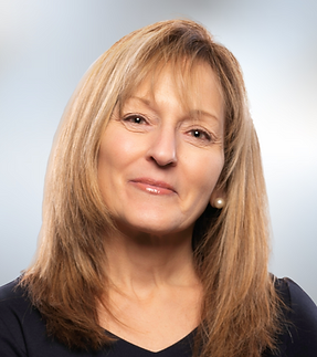 Female headshot with white shirt and dark hair up in bun