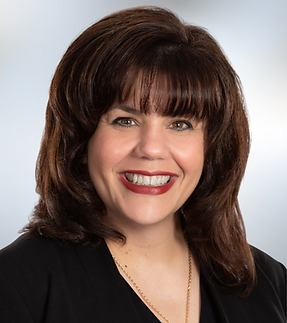 Female headshot with white shirt and dark hair up in bun
