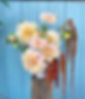 An arrangement of large pink/cream toned Cafe Au Lait Dahlias, Jasmine and trailing rust coloured Amaranthus in front of a bright blue/green door