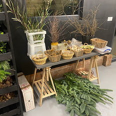 An image of a table with baskets and buckets on top containing foliage, dried fruit and other items to use as decoration on the wreathes