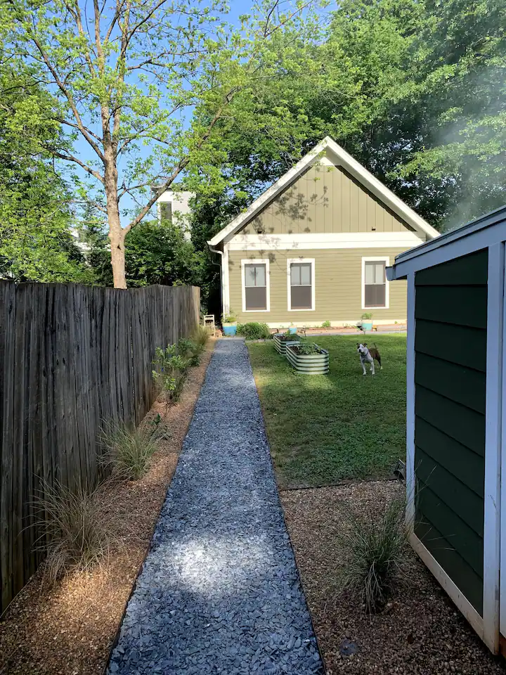 Gravel path through a large backyard leading to a small home