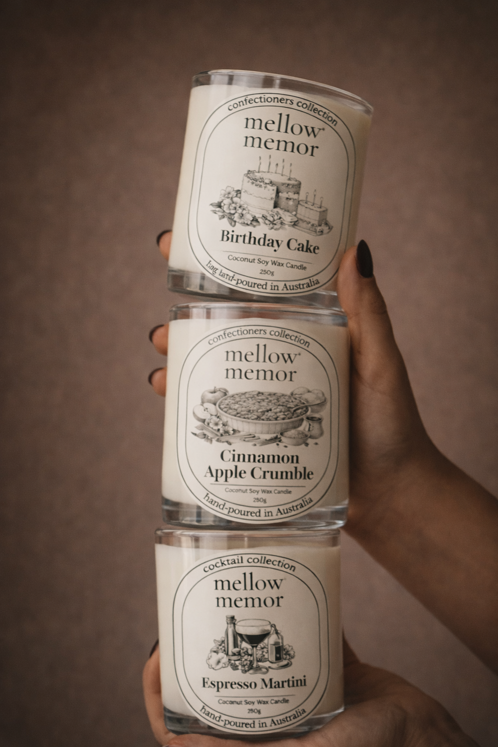 Hands holding a stack of Mellow Memor Birthday Cake, Cinnamon Apple Crumble and Espresso Martini candles