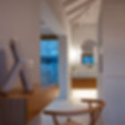 Atmospheric evening view from the vanity nook toward vaulted white ceilings, stone masonry outside, and warm en-suite bathroom lighting.