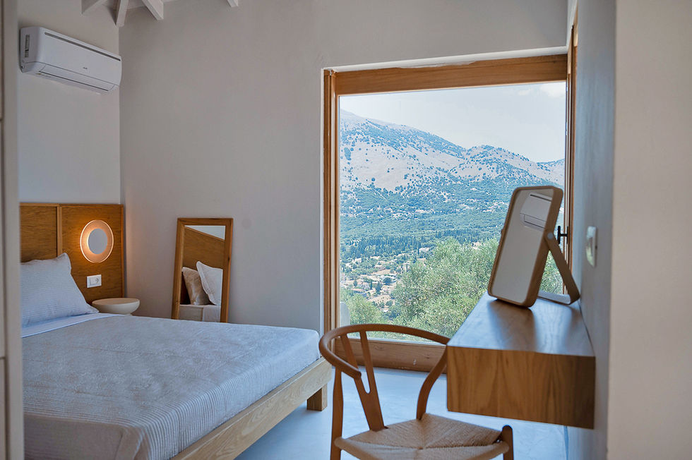 Luxury bedroom at Villa Menta Verde in Greece featuring natural wood furniture and panoramic mountain scenery.