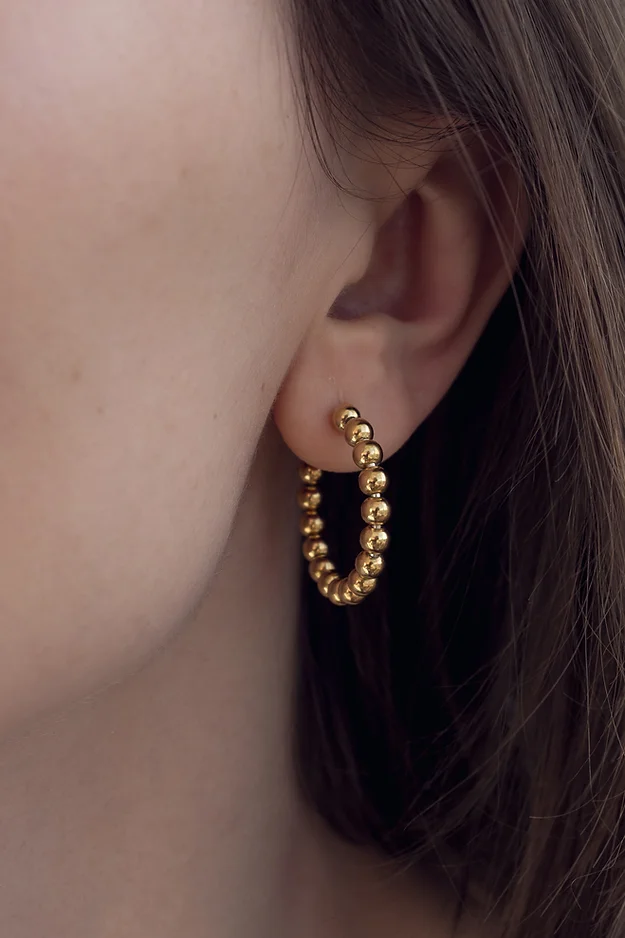 Gold Bola earrings on the ears