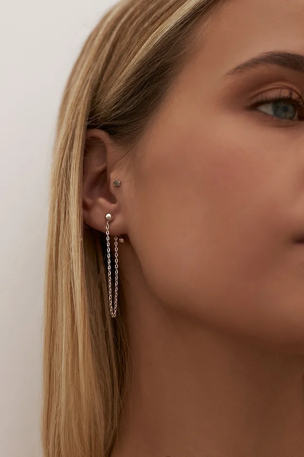Tragus piercing in combination with stud earrings with chain