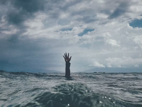 an arm reaching out of the ocean, symbolizing being emotional overwhelmed.