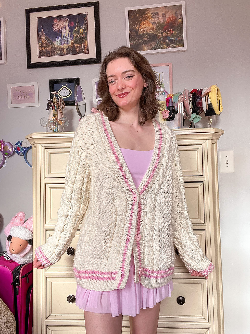 A girl wearing a pink skirt, pink top, and cardigan.