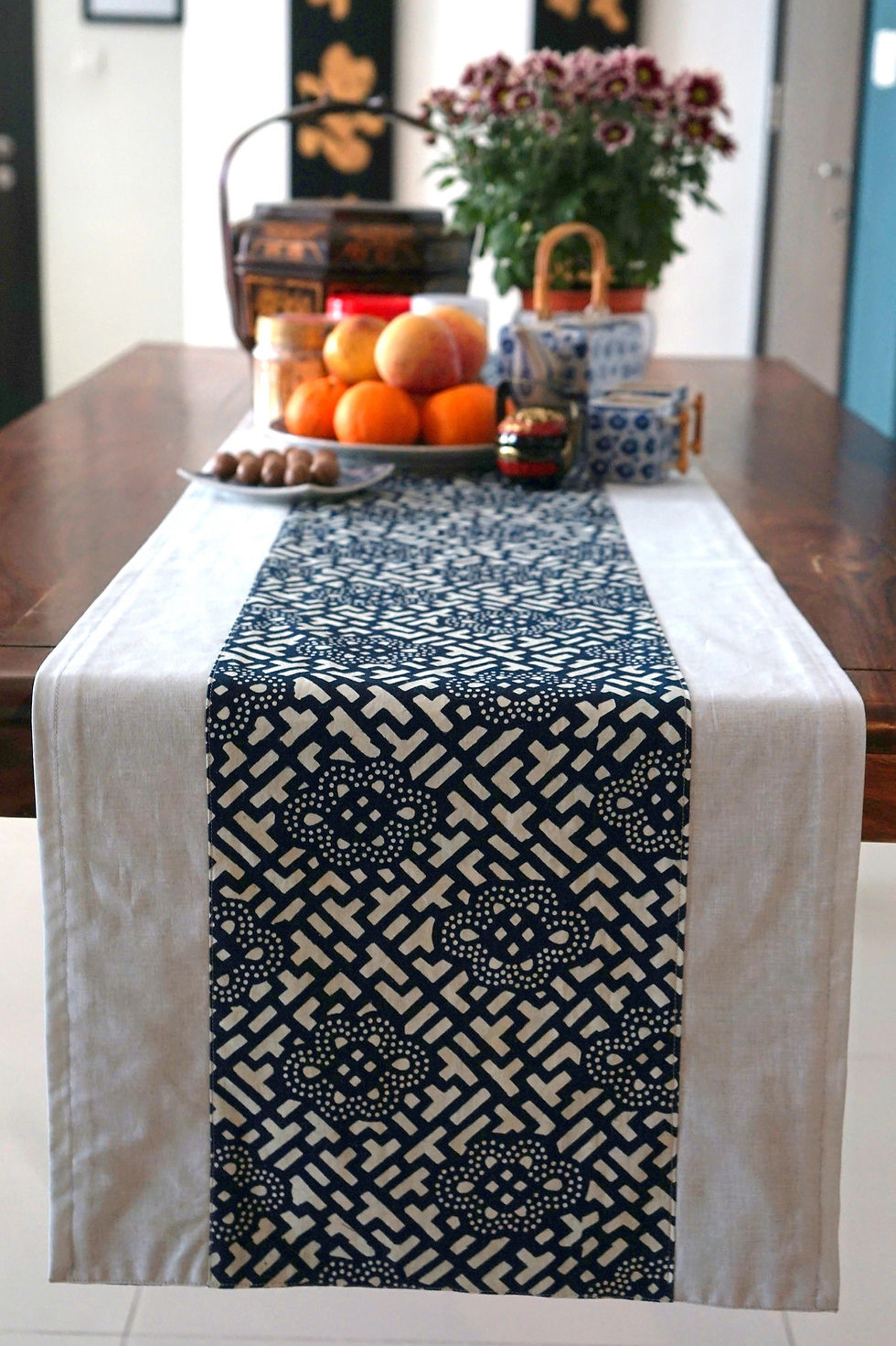 Table Runner overhanging off dining table with flower pot fruits tea pot cups