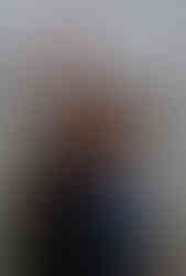 a newly engaged couple wearing a mixture of blues and blacks in front of lake in a small midwestern town.