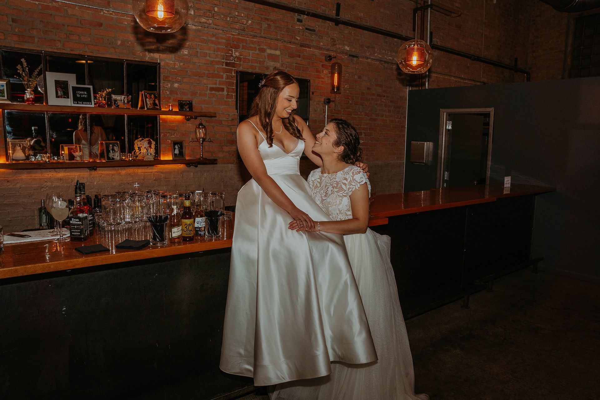 a couple at their wedding day taking photos in a venue that is all exposed brick and moody lighting
