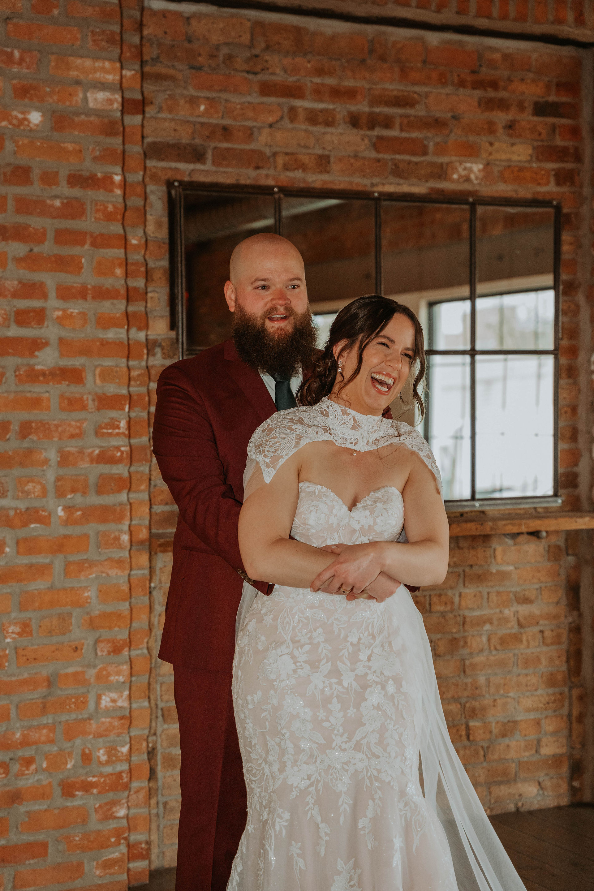 a couple at their wedding day taking photos in a venue that is all exposed brick and moody lighting