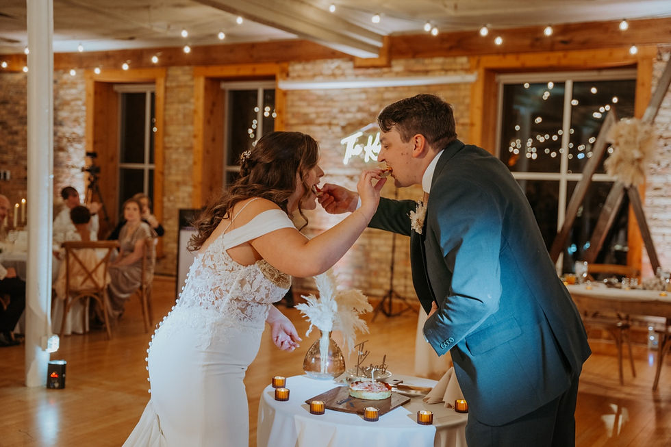 A bride and groom feed one another pieces of a small pizza in place of their wedding cake during their reception inside of The Highland Loft