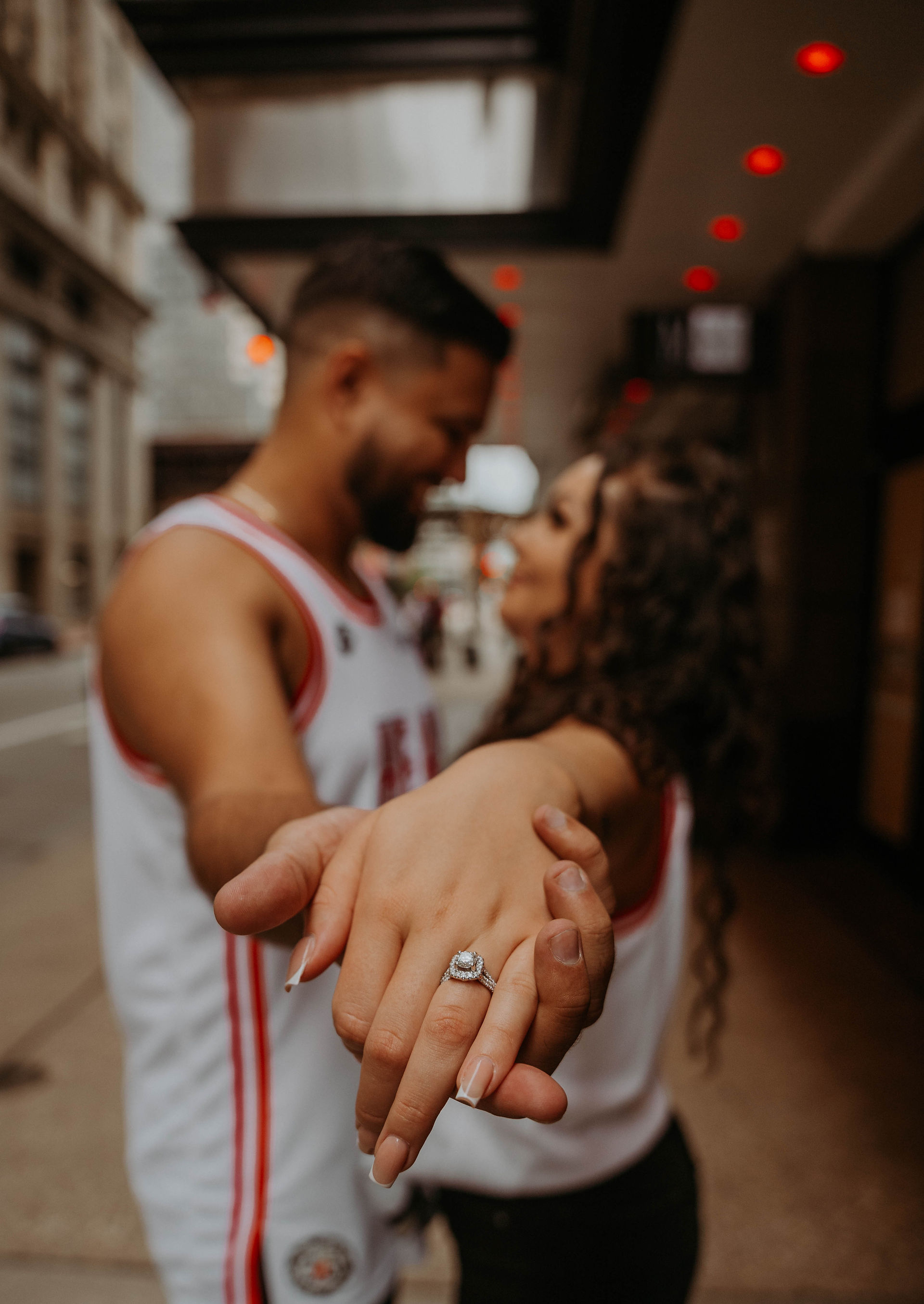 a couple taking photos downtown with very tall cream colored buildings 