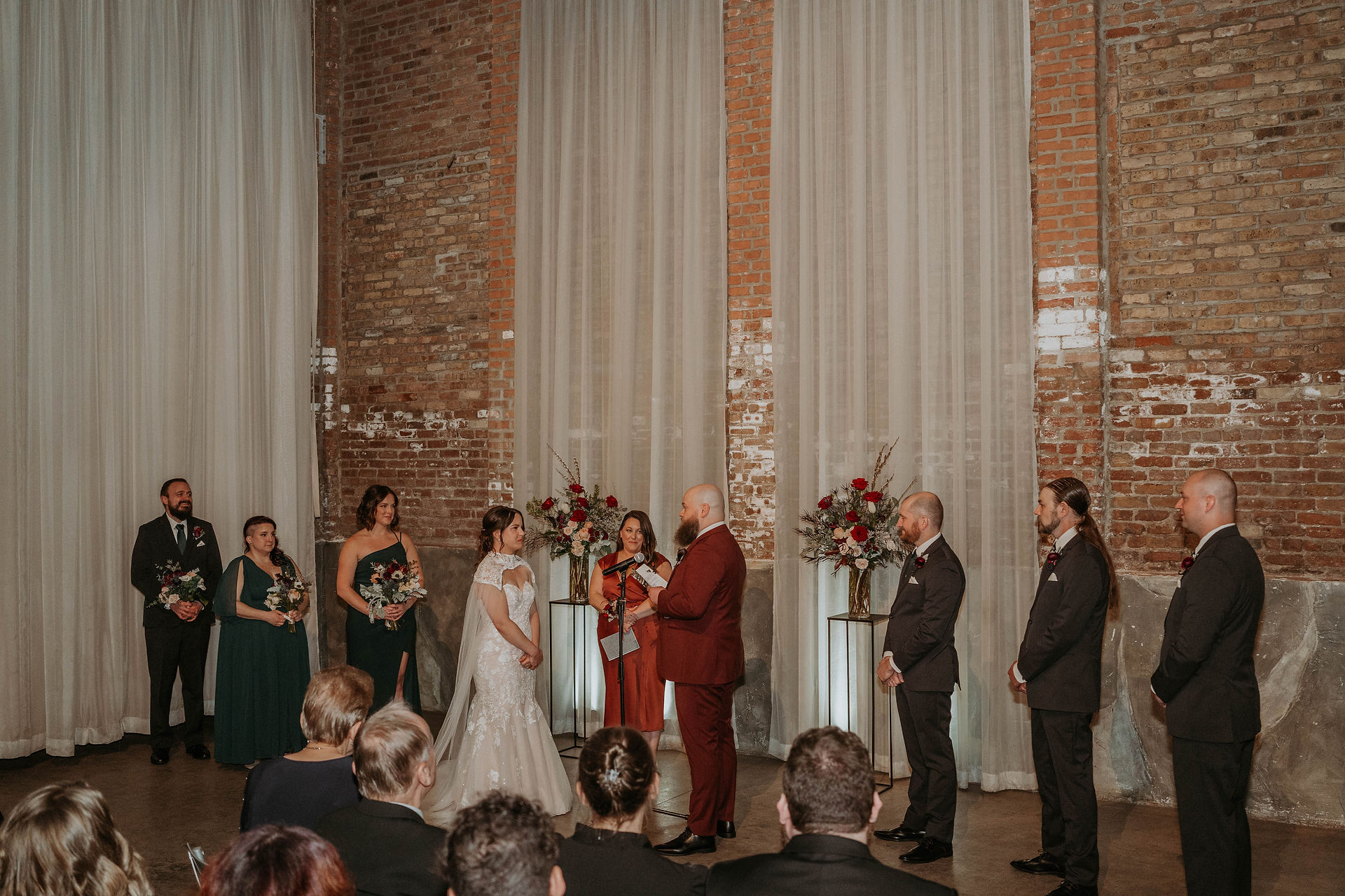 a couple at their wedding day taking photos in a venue that is all exposed brick and moody lighting