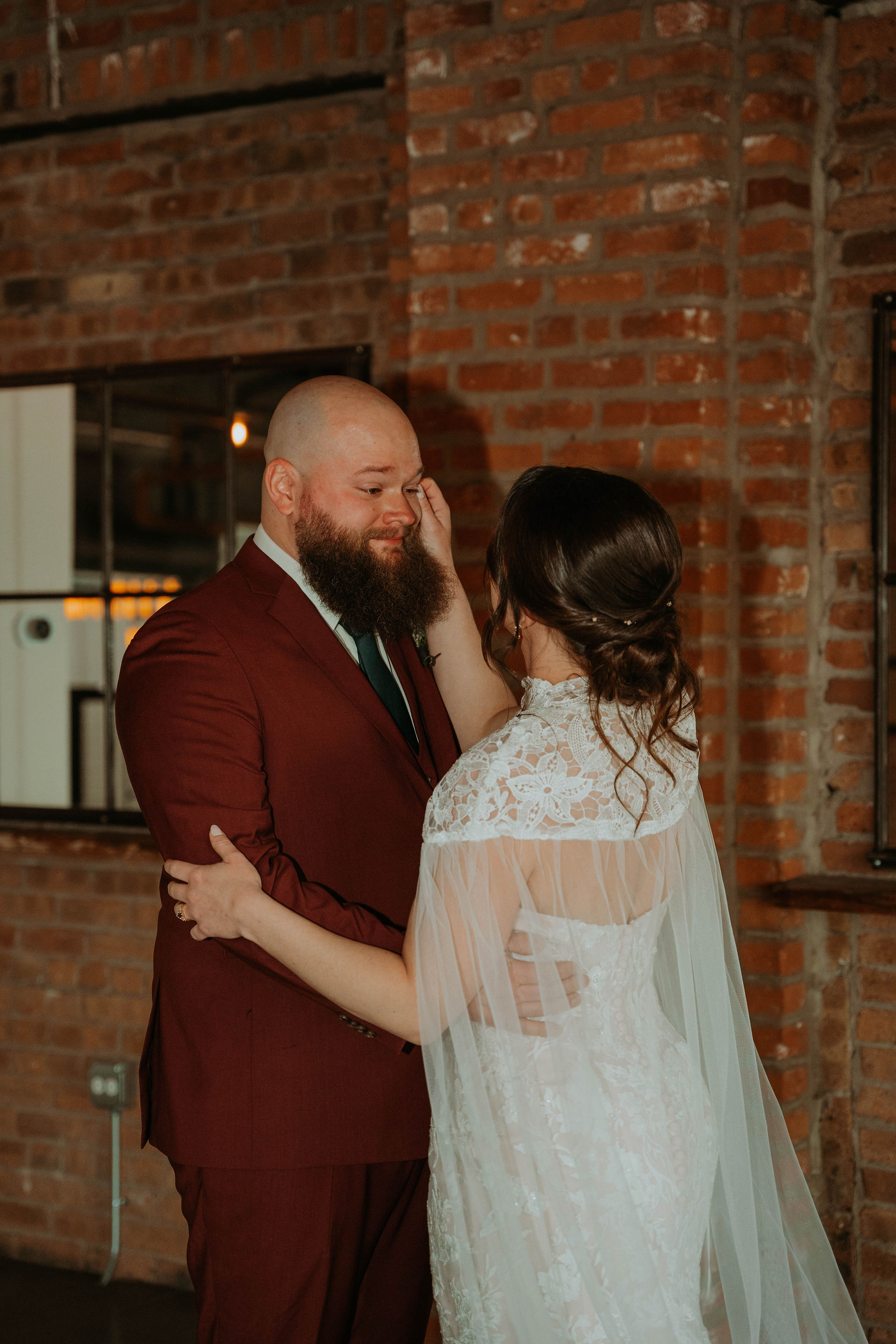 a couple at their wedding day taking photos in a venue that is all exposed brick and moody lighting