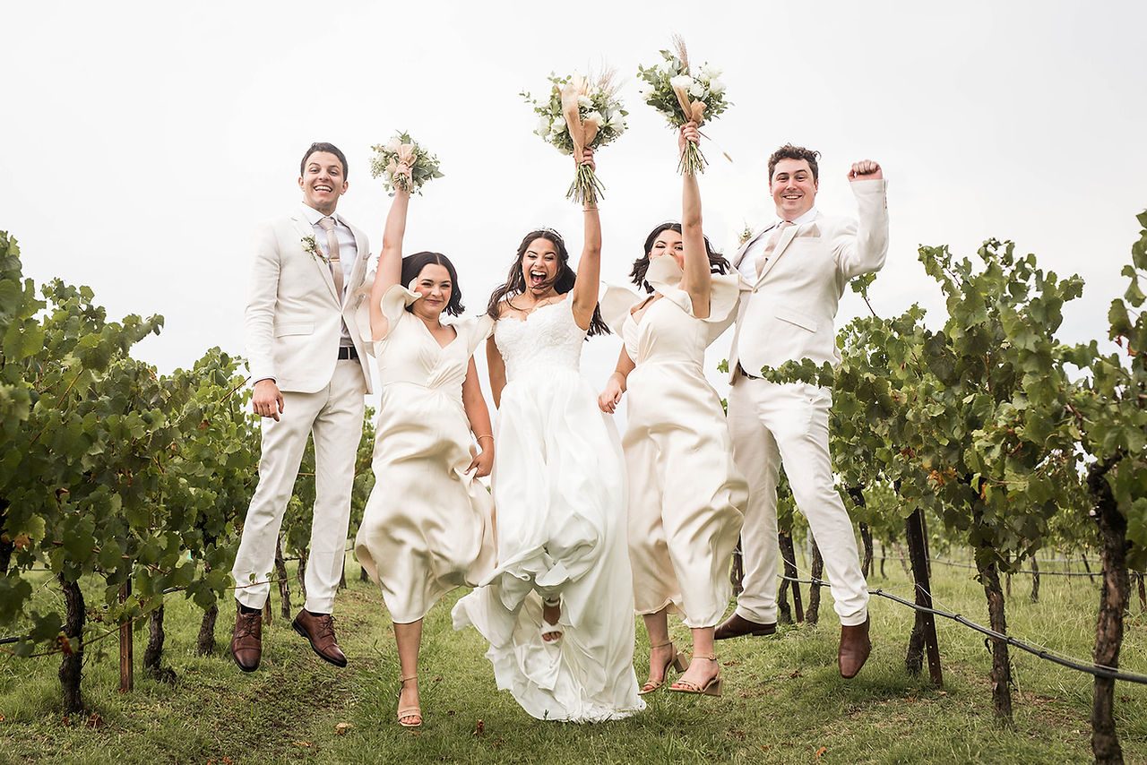 bride and her bridesmaids jumping in a vineyard