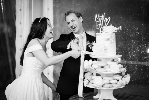 bride and groom cut their wedding cake and laugh