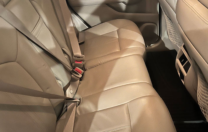 An Image of a fully detailed car interior's back passenger seats. with a tan colored upholstery