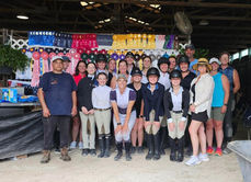 Group of people standing in front of a wall with different colored ribbons on it. 