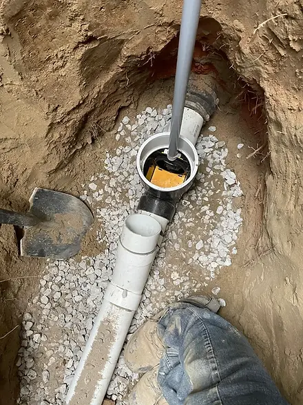 Drain repair with new PVC pipe installation in gravel bed, highlighting importance of timely pipe repairs.
