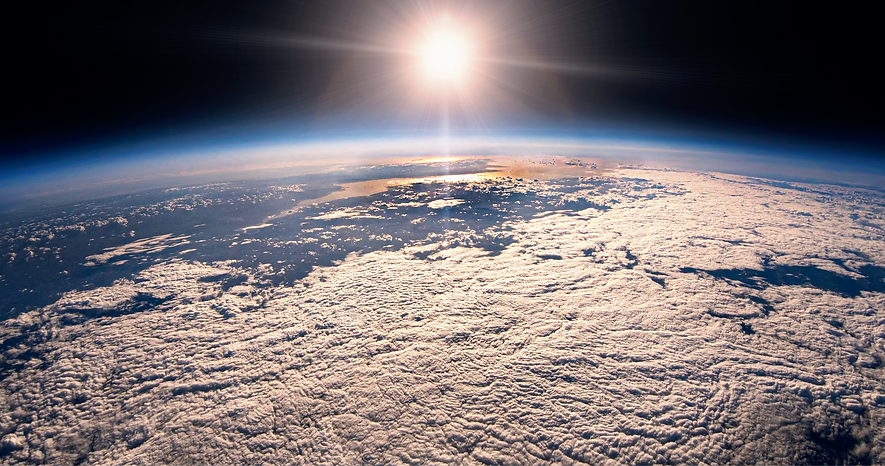 Earth below the blackness of space with shining sun