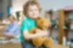 Toddler smiling and hugging a teddy bear