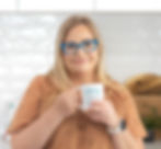 Nina holding coffee mug which says 'I am calm' Nina is wearing a brown top and looking at camera