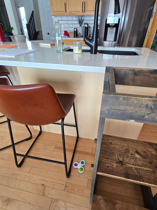 EFORE photo of the kitchen island prior to the added wood panel, showing the original finish at the base beneath the white quartz countertop.