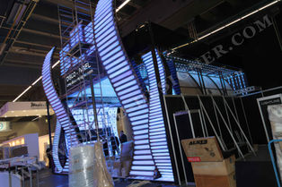 The booth is composed of LED panels and climbing walls, which can be used for exhibition display or brand promotion during the fair in L drafting form design drawing The installation area features a high ambient light effect with bright colors and white lighting that creates an atmosphere full of creativity. A man stands on top to do wall climbing construction work.