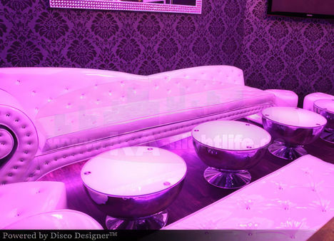 A photo of the interior design and decoration work for a "masculine designer" space in pink and purple colors, with a white ceiling featuring LED lighting, a bar counter, and walls full of wine bottles.
