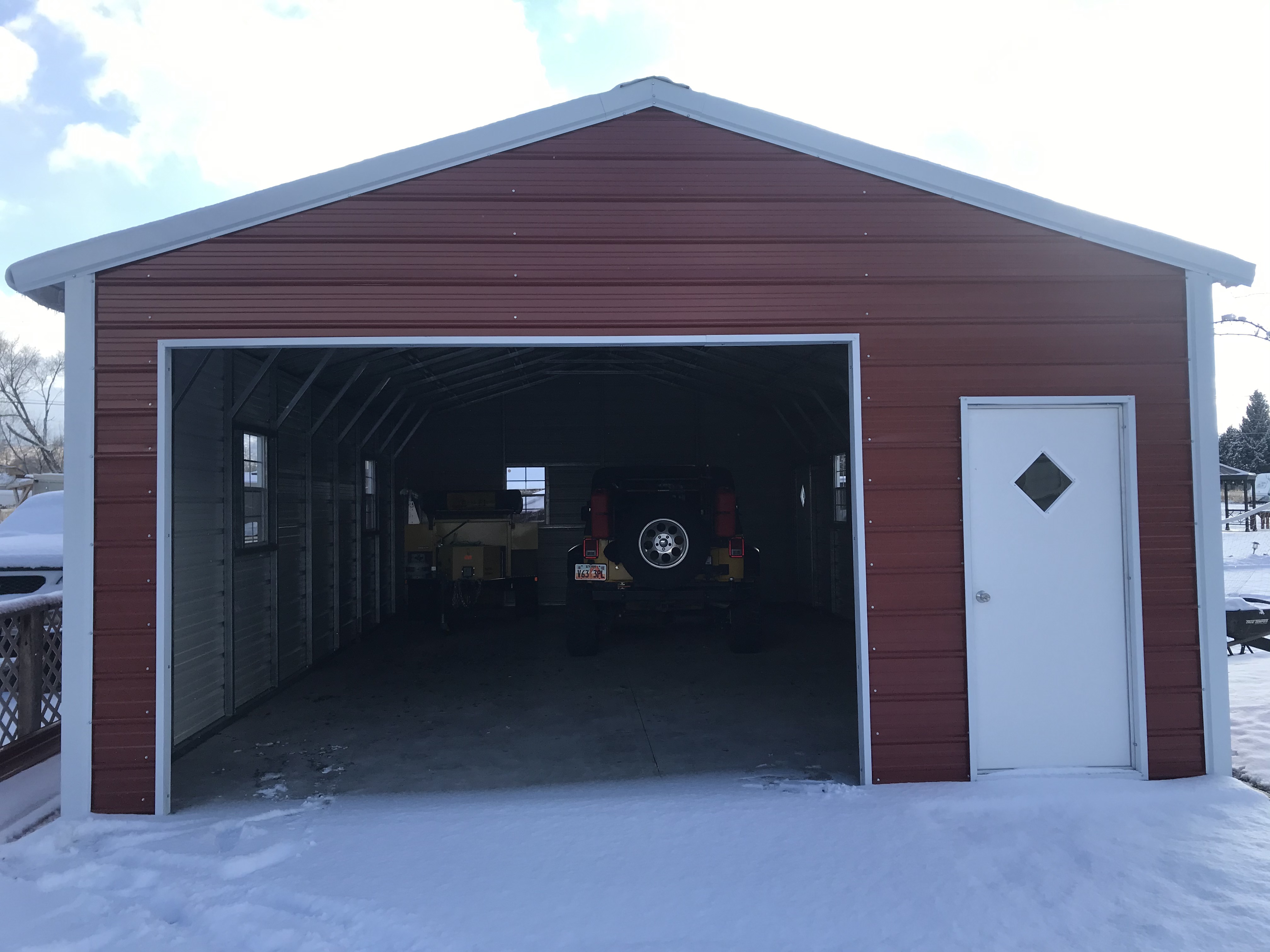 Burgundy 20 by 36 metal garage with an open garage door in Santaquin, Utah