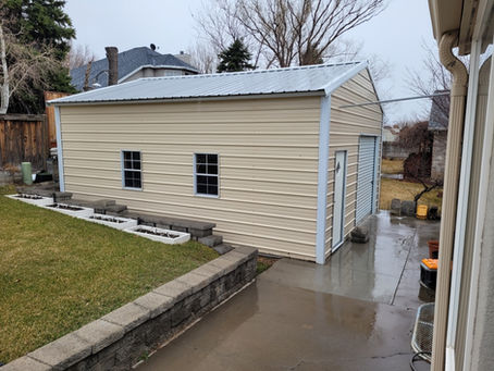 Metal garage with windows beside a concrete driveway.