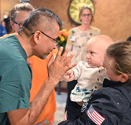 Neonatologist interacting with neonatal baby carried by mother